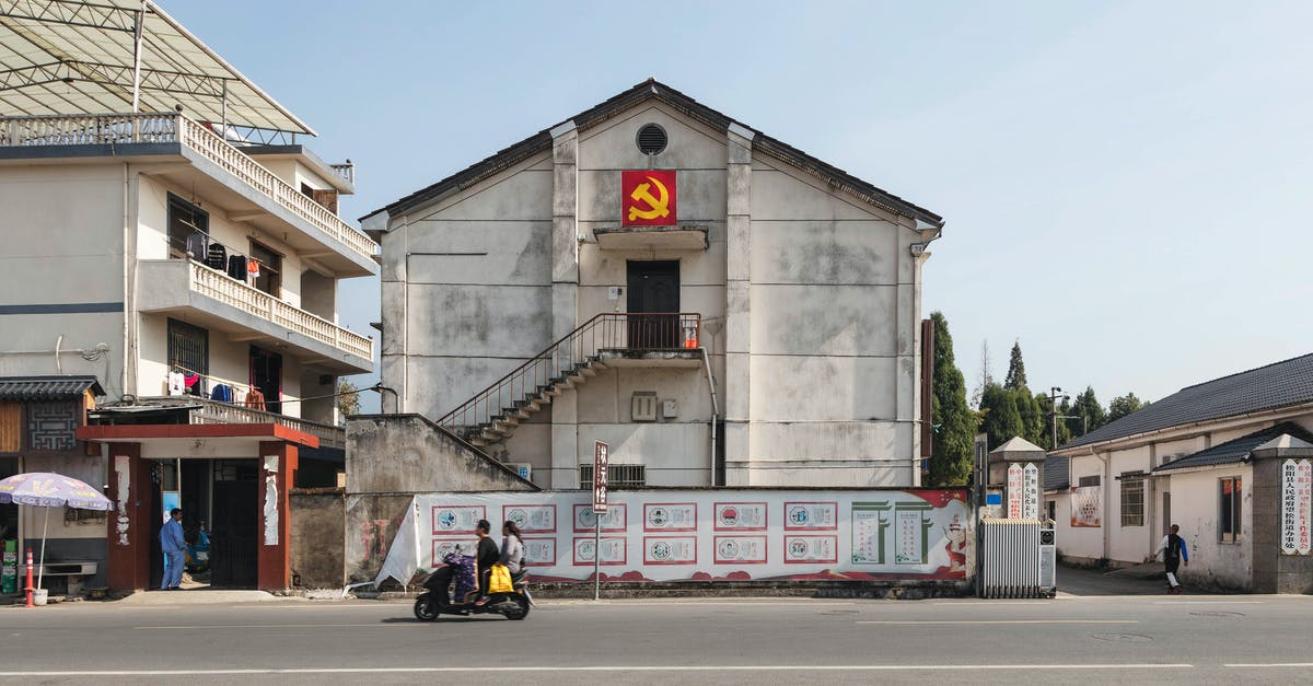 Do road signs showing a country and a city as destinations really exist? - Exteriors of low level buildings decorated with hammer and sickle flag located in suburban area in Communist country