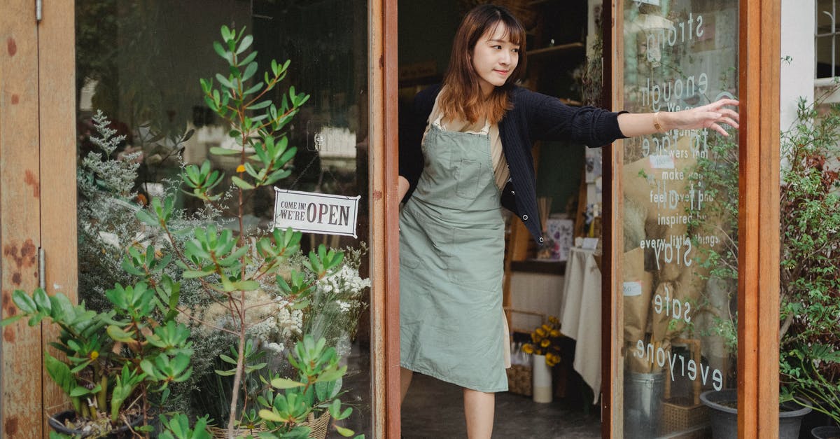 Do stores on Takeshita street open the 1st of January? - Tranquil florist in apron opening glass door of flower shop in daytime in city