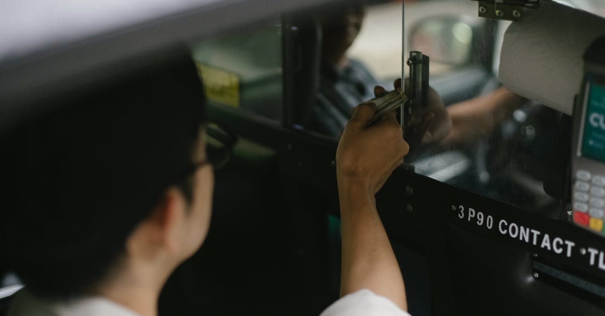 Do taxis accept non cash payment in Zurich - High angle of crop young male passenger in white shirt sitting in automobile and giving dollars to driver