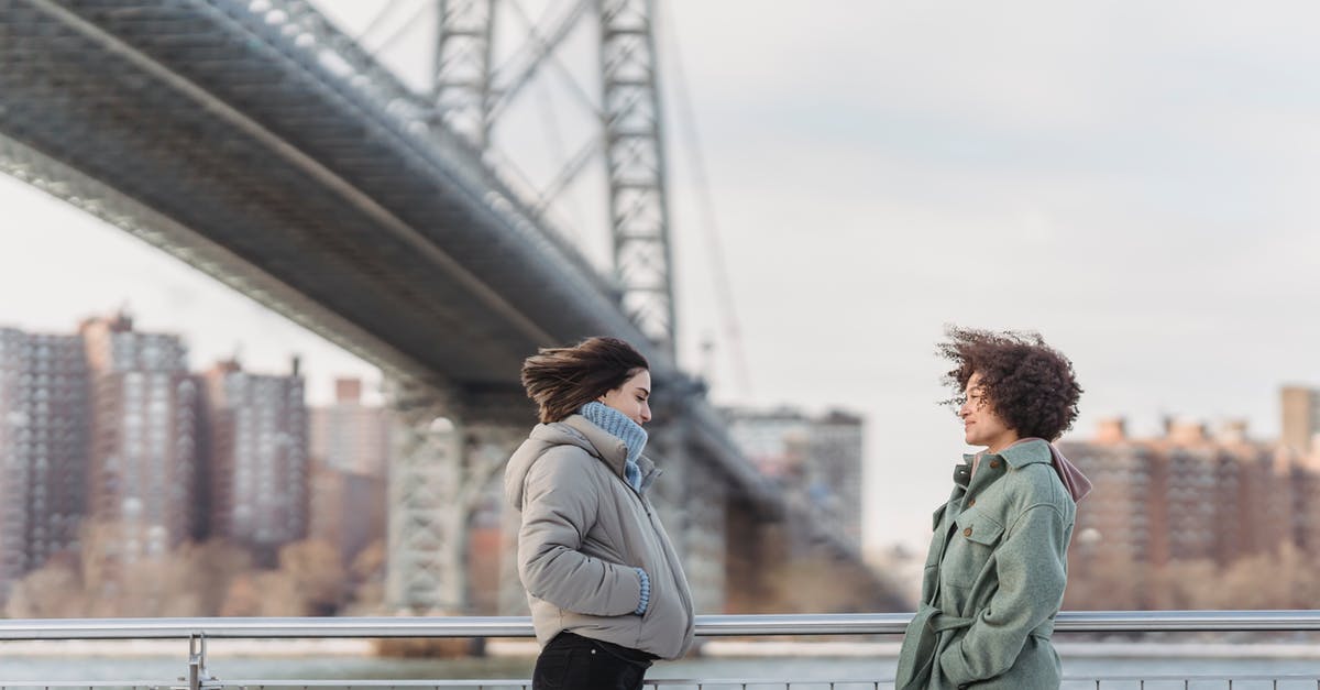 Do the UK and USA share immigration information? [duplicate] - Side view young female friends in warm clothes having conversation and standing face to face on New York City embankment on cold winter day