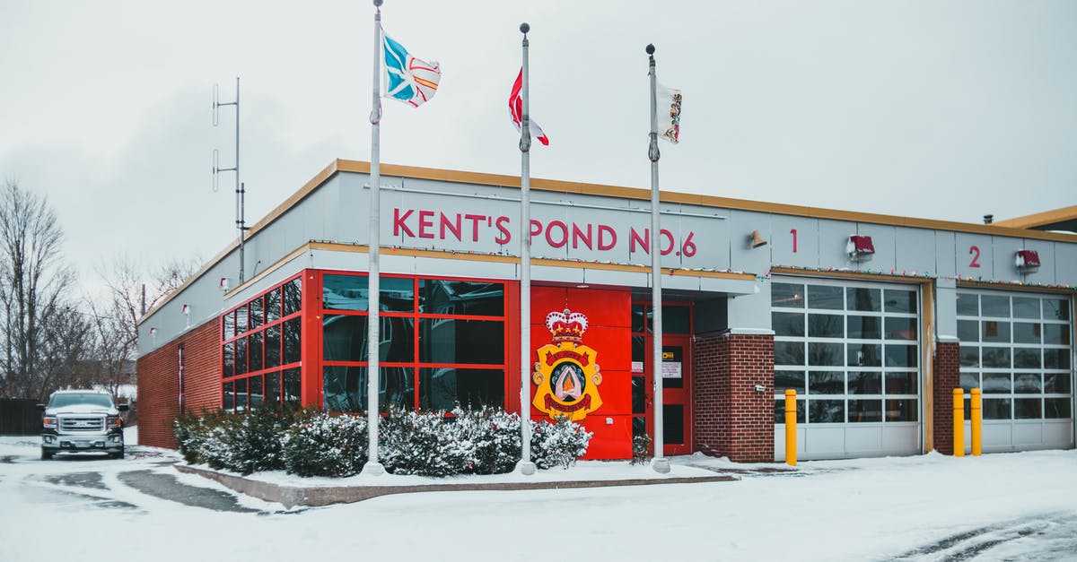 Does a Canadian permanent resident need a transit visa in Canada? - Building facade against flags in winter city