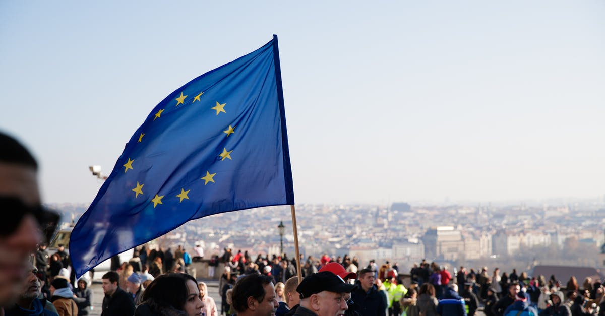 Does a Japanese citizen need a visa for European Countries? - Crowd of people walking on street with waving flag of European Union Courtesy during protest in city against residential buildings