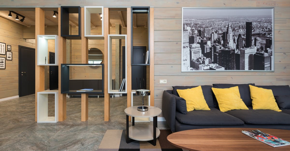 Does a Schengen Residency permit function as a multi-entry visa? - Modern apartment with sofa placed near round table with stylish geometric shelves separating living room from corridor