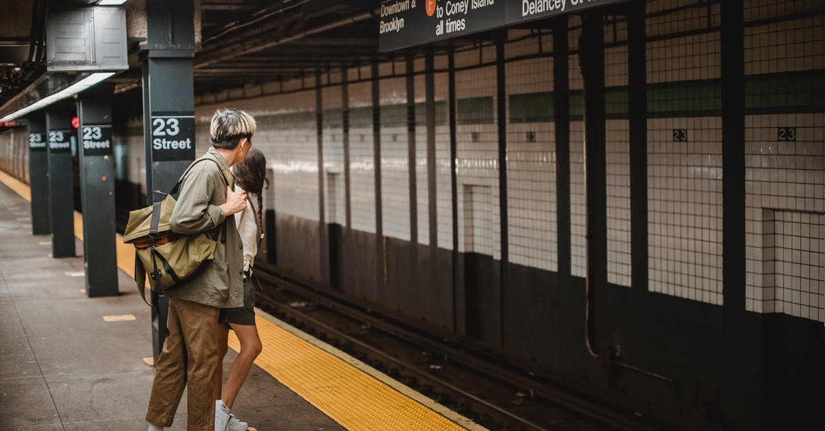 Does Amtrak ever stop at non-Amtrak (commuter only) stations? - Side view of unrecognizable young man and woman in trendy outfits and backpack looking away while waiting for train in underground station