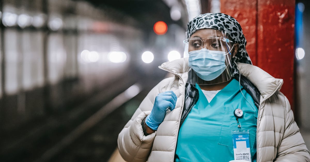 Does Amtrak ever stop at non-Amtrak (commuter only) stations? - Serious plump African American nurse in uniform and outerwear wearing face mask and latex gloves standing with takeaway coffee standing on metro station platform and looking away thoughtfully