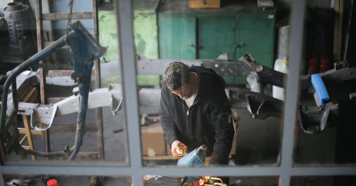 Does an anti scuff spray for luggage exist? - From window view of adult male worker in workwear standing at workbench and fixing metal detail while working in modern garage