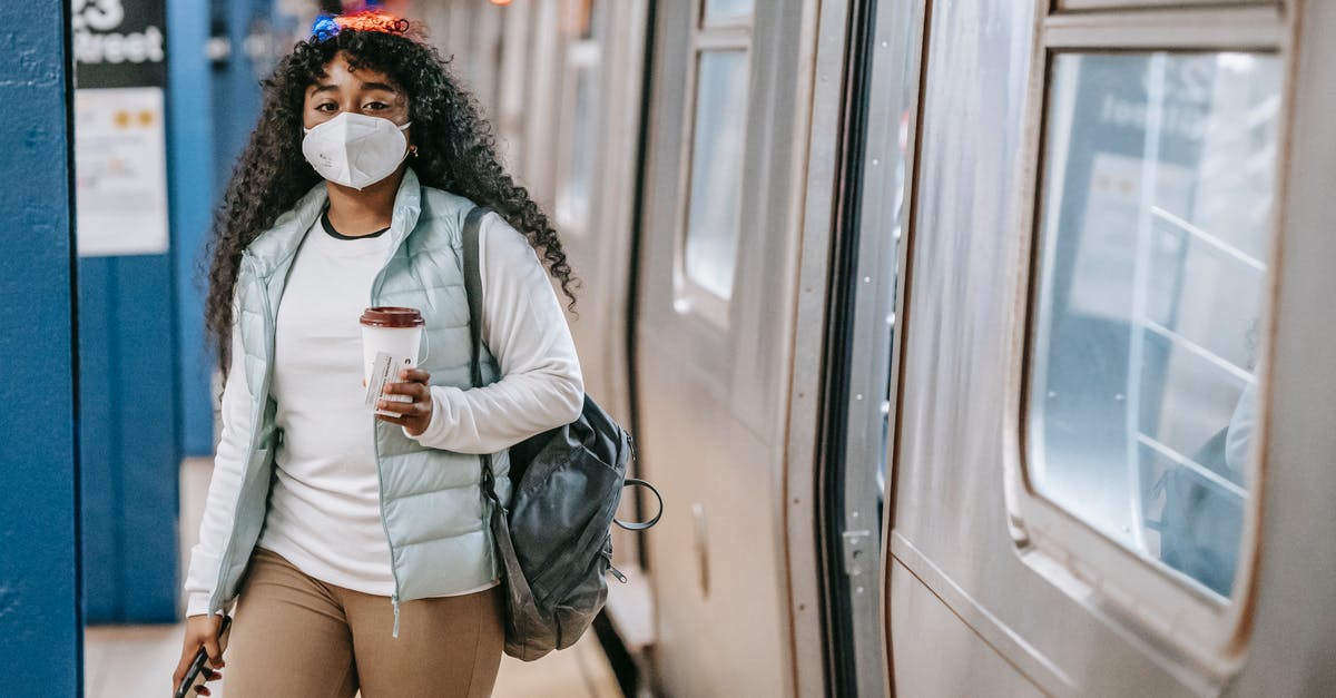 Does any passenger train go between the United States and Mexico via San Ysidro? - Calm black woman with coffee wearing medical mask standing in metro