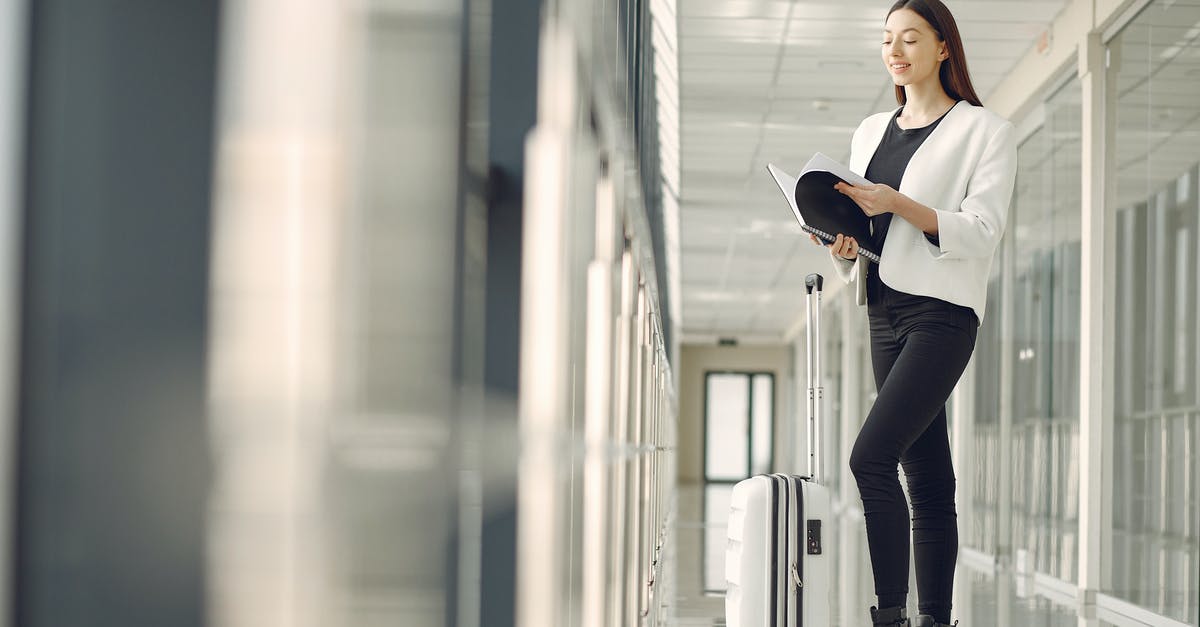 Does Belo Horizonte airport have an international transit area? - Full body of slim female businesswoman in formal clothes with suitcase standing in airport hallway and reading note in notebook while waiting for flight