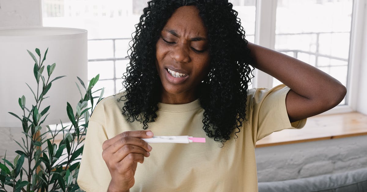 Does Delta require covid test before domestic flight? - Frustrated African American female in casual clothes looking at pregnancy test in hand while standing in light living room at home