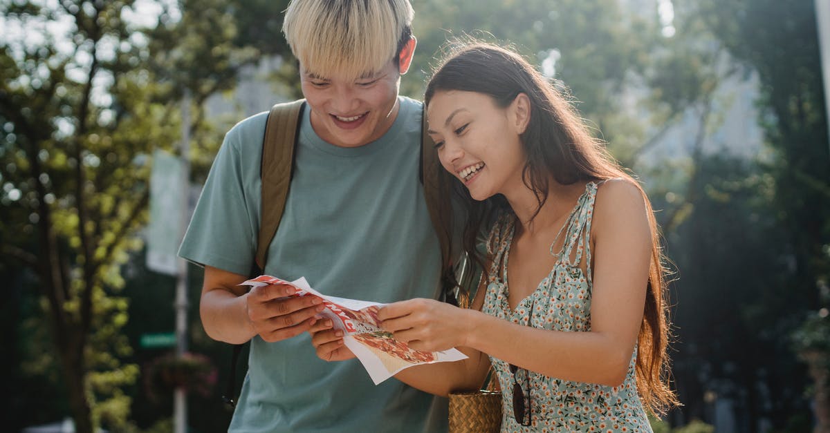 Does Google Maps take into account hills/inclines for route times? - Cheerful multiracial couple of tourists watching map in city