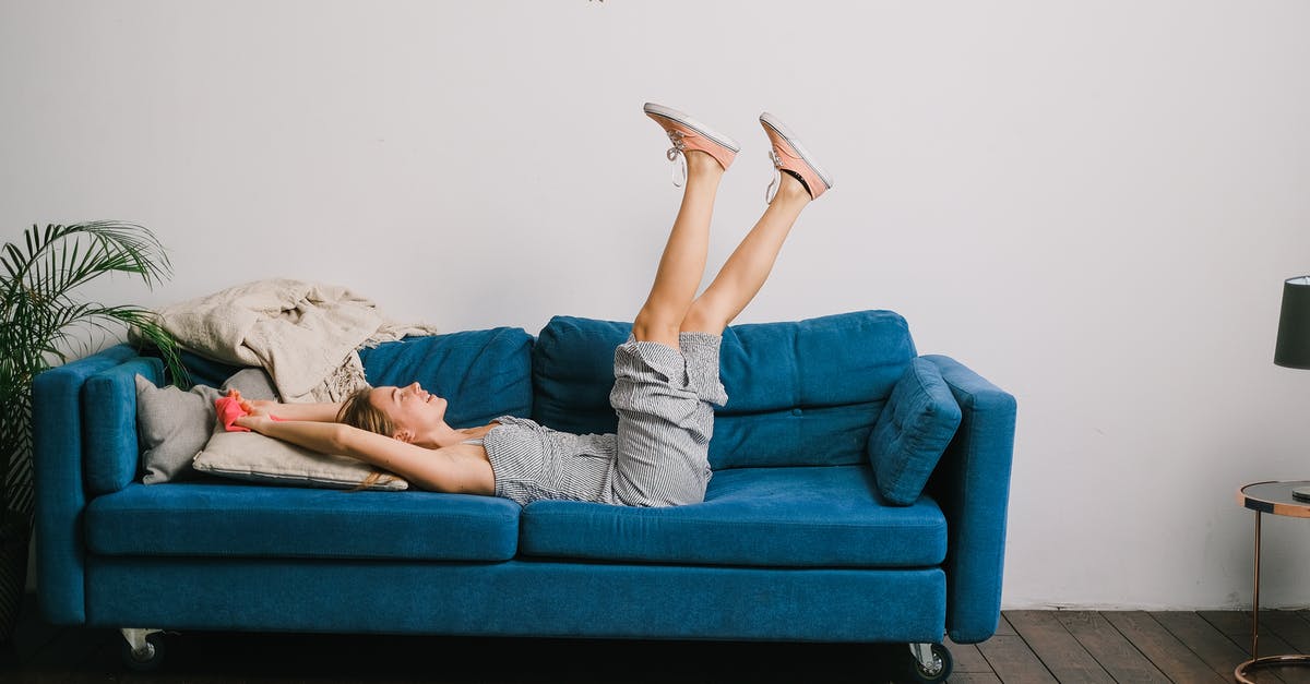 Does Icelandair have a lounge in Berlin? - Side view of cheerful young woman with rag and raised legs lying on sofa after housework