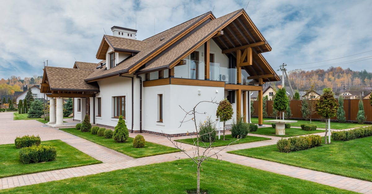 Does issuing a residence permit revoke a Schengen visa? - Exterior of modern cottage house with columns and balcony surrounded by green grass and trees