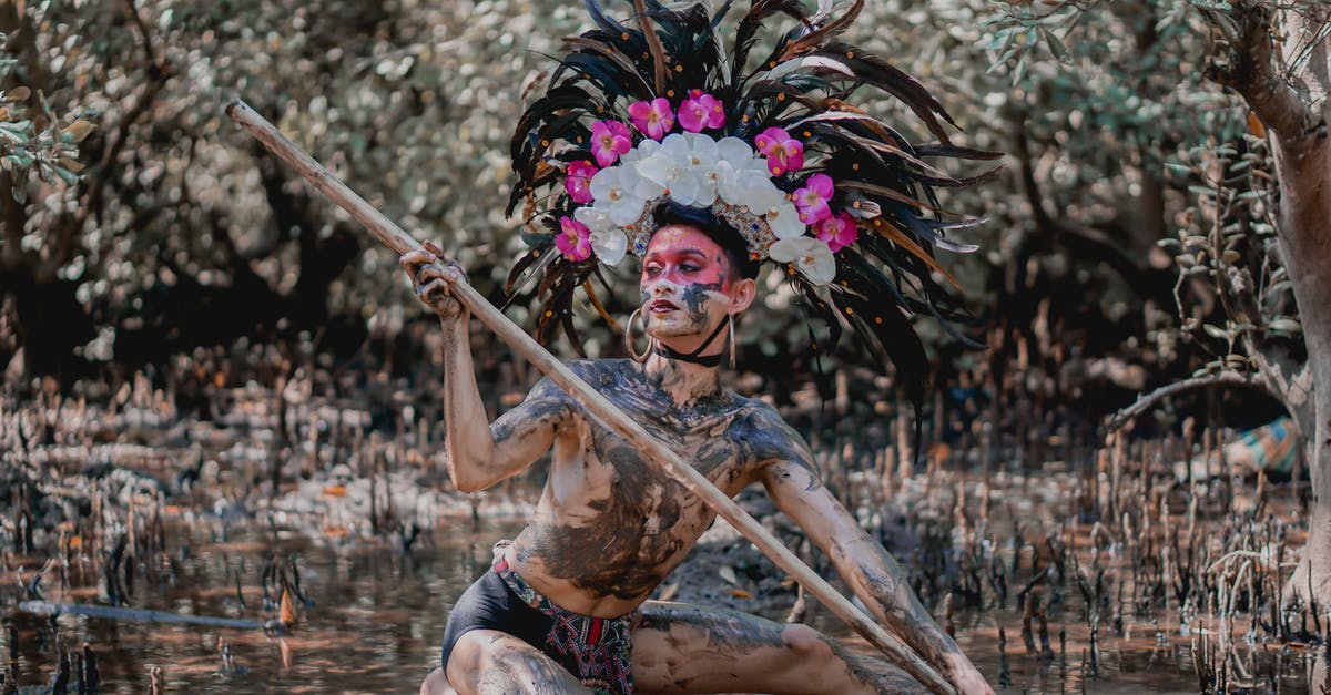 Does Korea have any mud festivals in autumn? - Person Wearing Feather Headdress Holding Wooden Stick While Kneeling on Mud