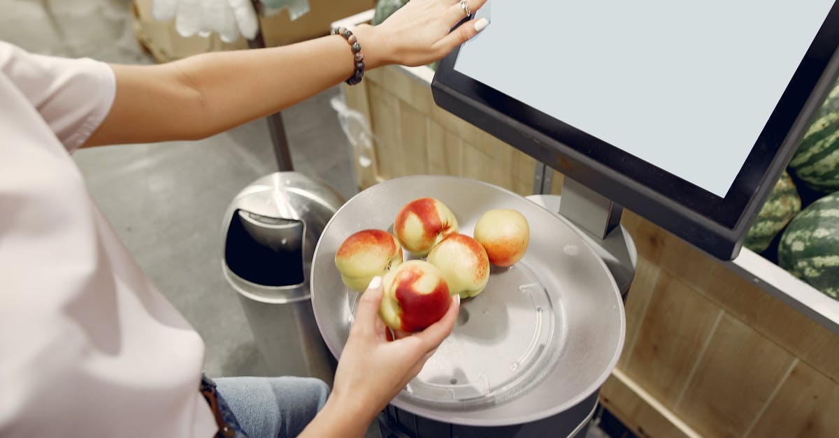 Does LOT strictly control hand luggage weight? - From above of unrecognizable woman touching screen of electronic scales and putting peaches while weighing peaches on scales in contemporary supermarket