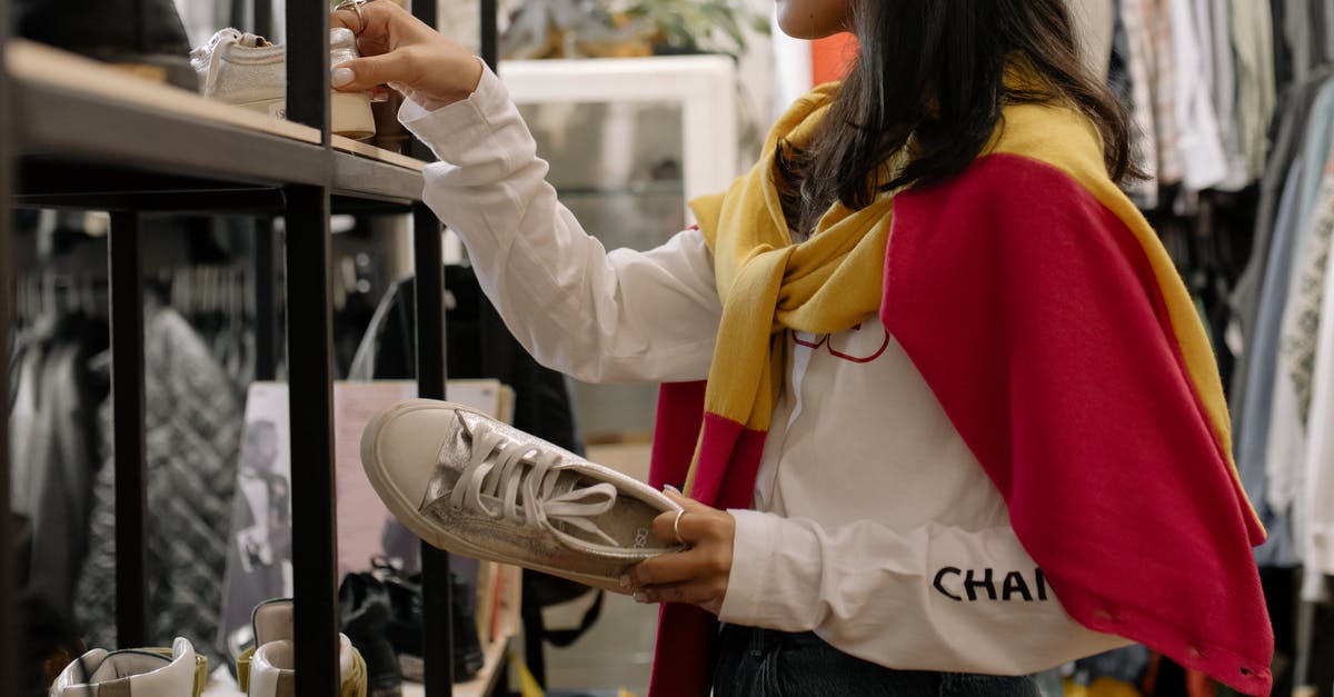 Does Taiwan have thrift stores? How to find them? - Woman in White Long Sleeve Shirt and Blue Denim Jeans Holding White Shoes