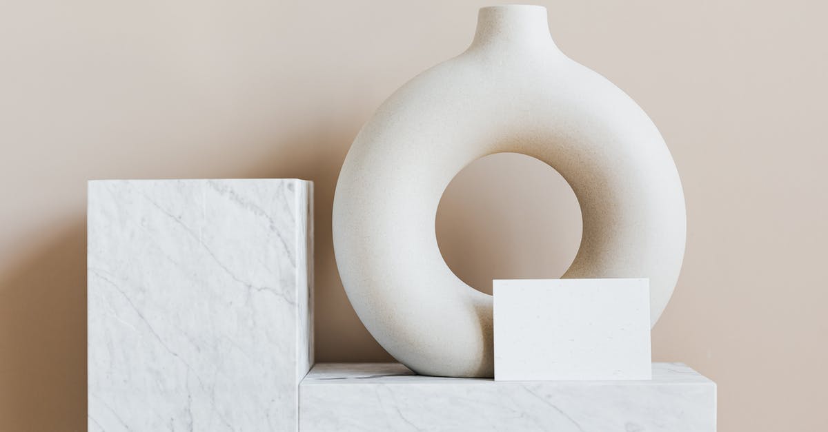 Does the cartography workshop where Christopher Columbus lived in Lisbon still exist? - Composition of creative white ceramic vase in ring shape with empty postcard placed on white marble shelf against beige wall as home decoration elements or art objects