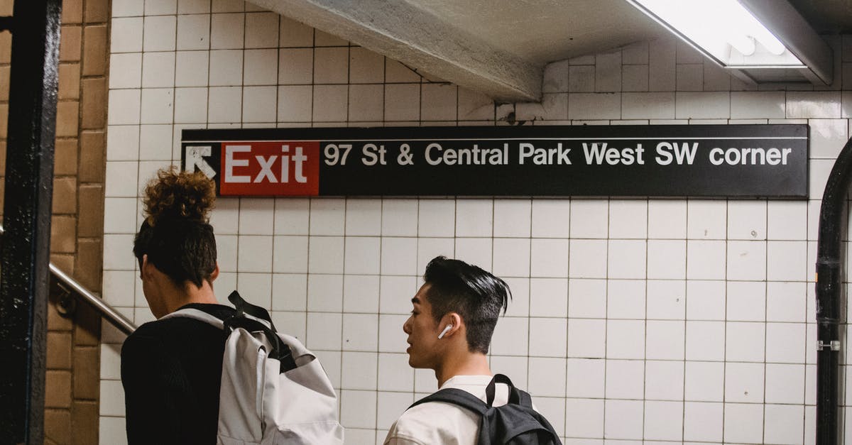 Does the PATH train keep to schedule? - Back view of ethnic male walking in subway station with friend while commuting to university