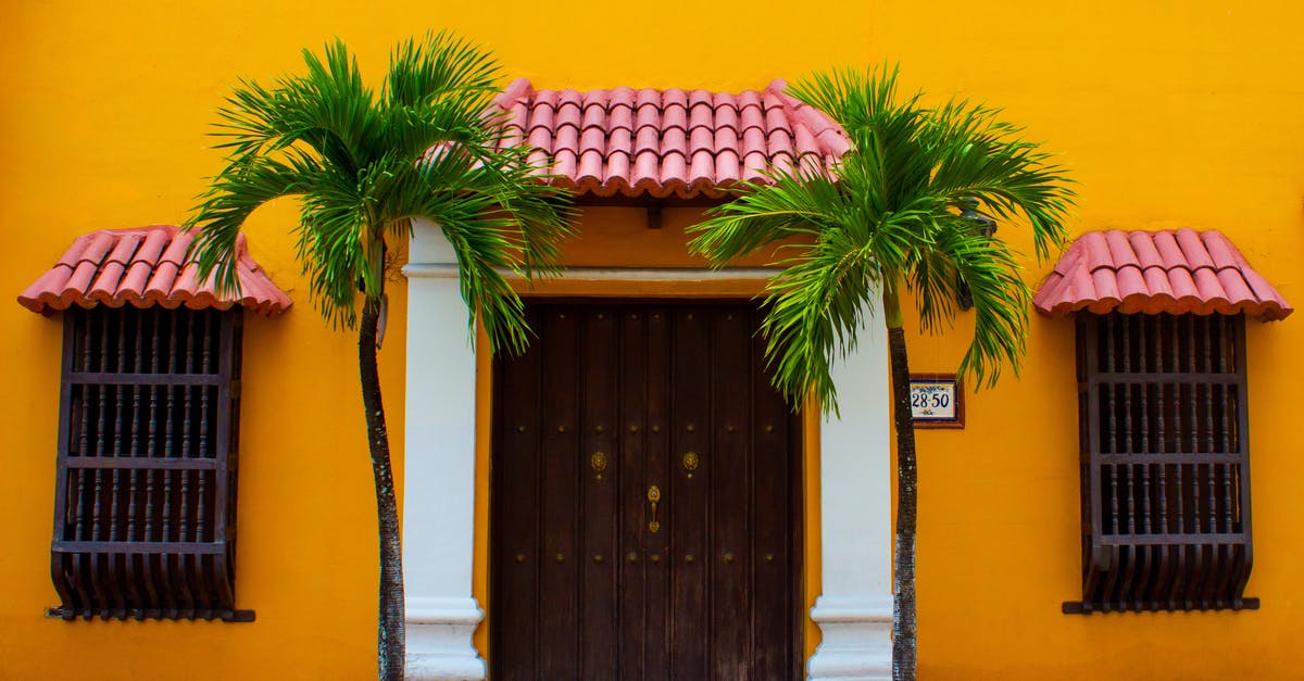 Does visiting Colombia hurts one's travel history? - 2 Green Palm Trees Beside Wooden Door