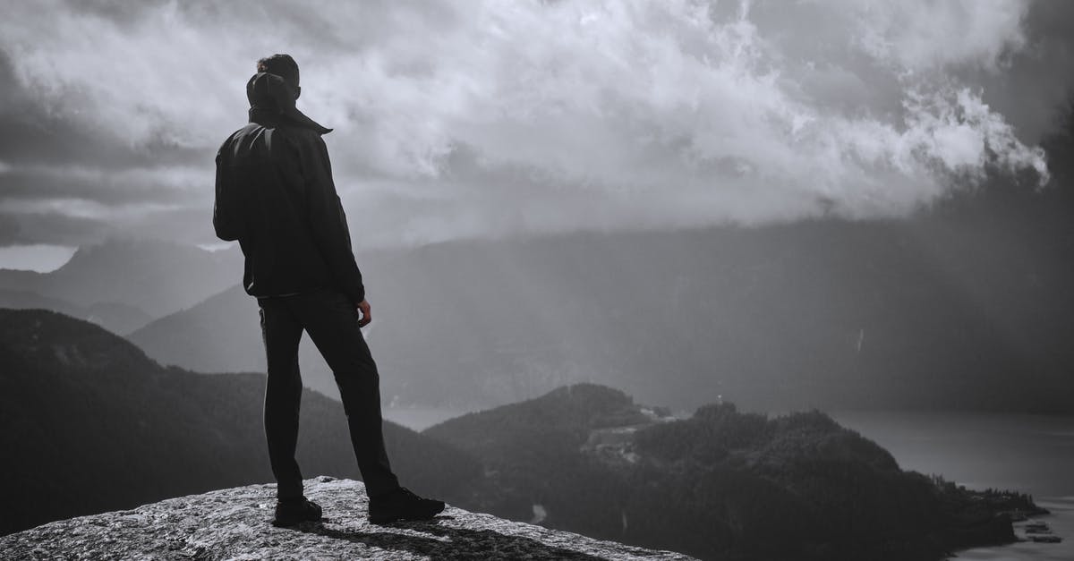 Does visitor status to Canada require an outgoing flight? - Man in Black Jacket Standing on Rock Formation