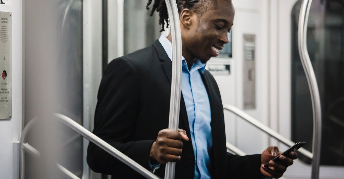 Dolomites in September end using public transport - Cheerful black man surfing net on mobile on subway train