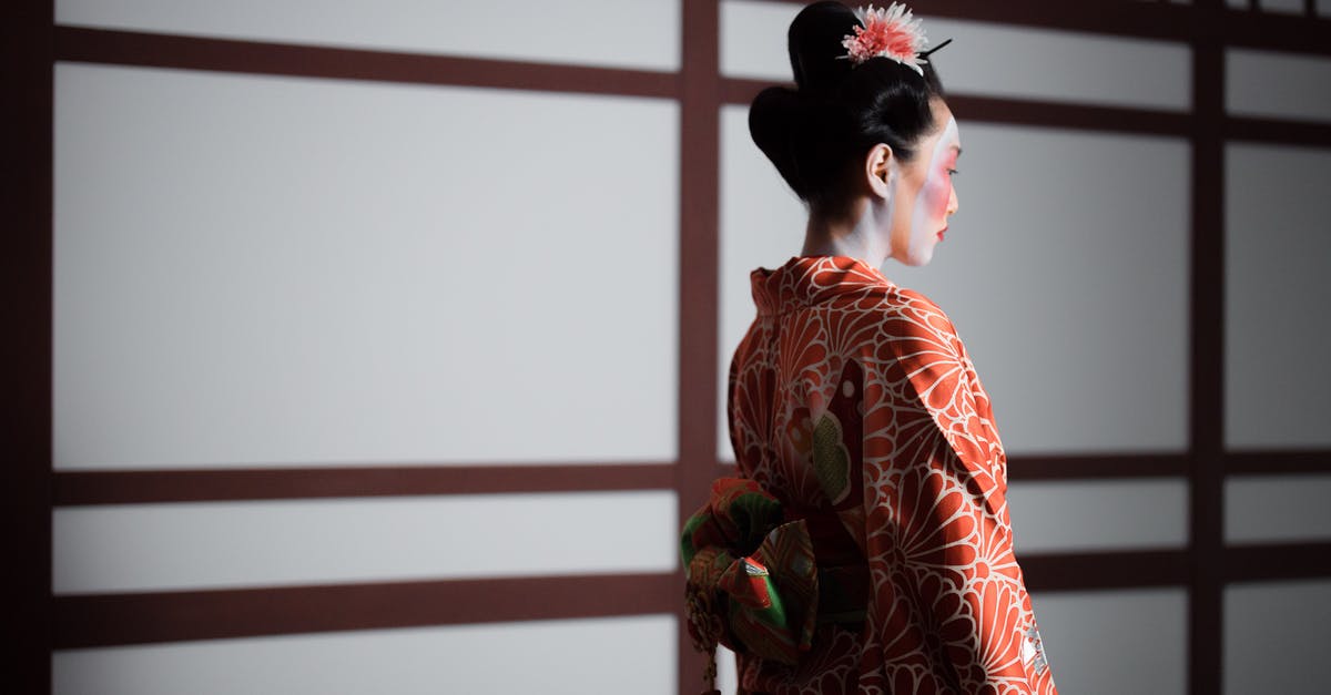 Dressing up as a Geisha/Maiko in Japan - Girl in Red  Floral Kimono Standing Near White Wall