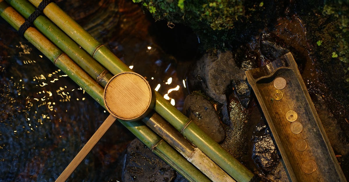 Drinking from the Chalice Well in Glastonbury (Sacred Spring in England) - Bamboo water pipes with dipper near brook