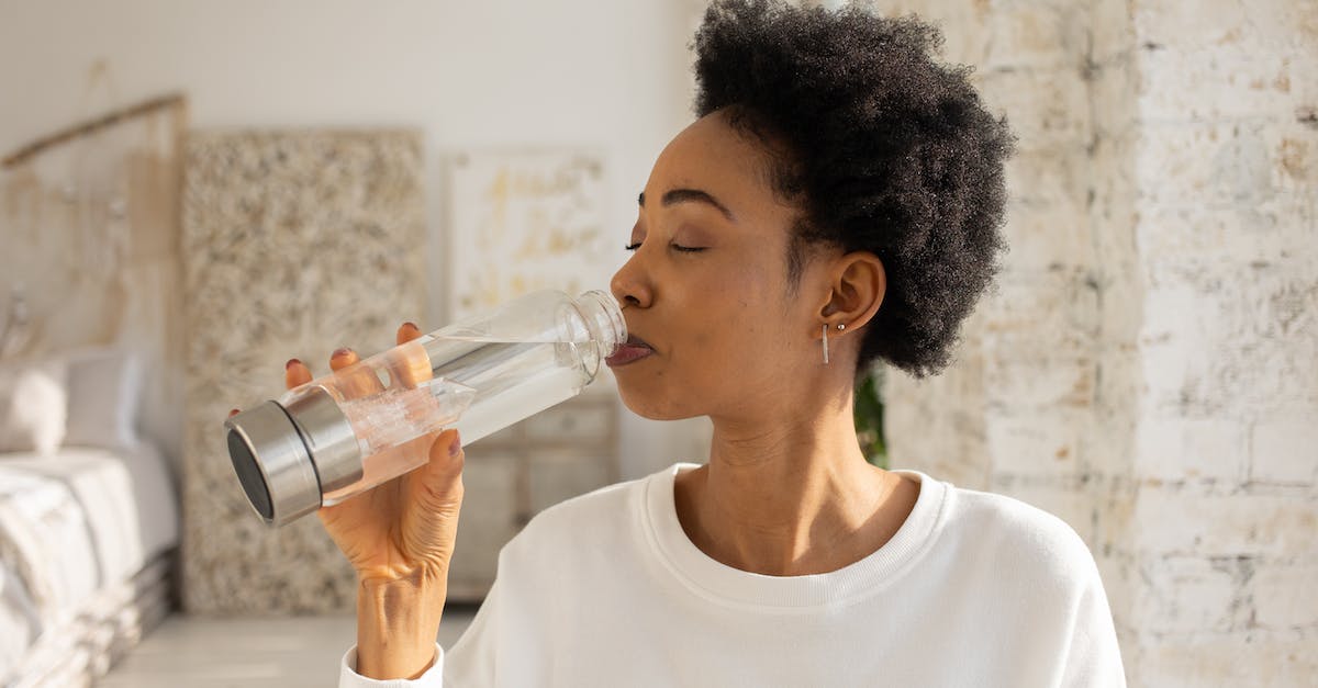 Drinking tap water in India - Woman in White Crew Neck Shirt Drinking from Clear Glass Bottle