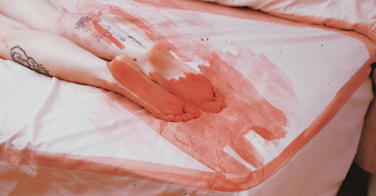 Driving a 21 foot tow truck flat bed [duplicate] - High angle of crop anonymous female lying on white bed with legs and feet with sheet covered with red lines and spots in light bedroom