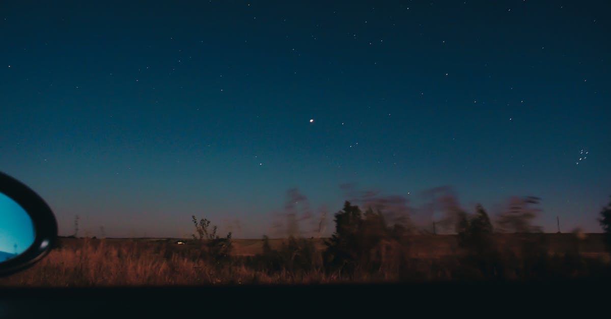 Driving a rental car through Colorado - View through moving car window of horizon line with dark star sky and blurred trees