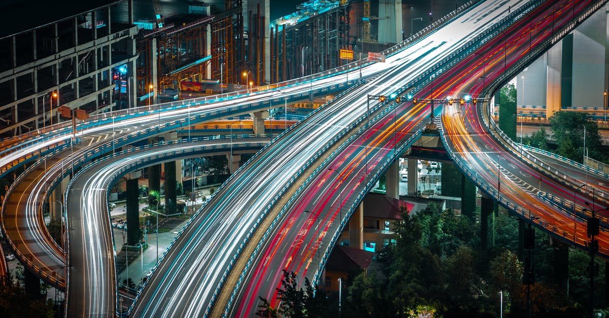 Driving from Belgium to Portugal - From above long exposure traffic on modern highway elevated above ground level surrounded by urban constructions in evening