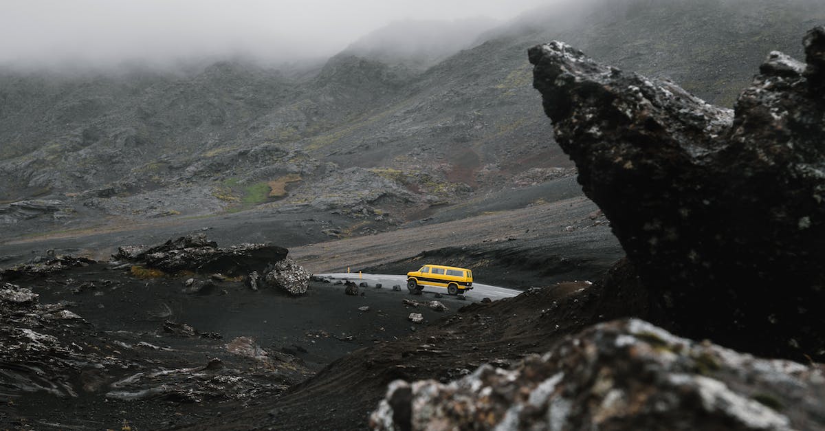 Driving in Iceland: a good idea? - Car driving on road between ridge under overcast sky