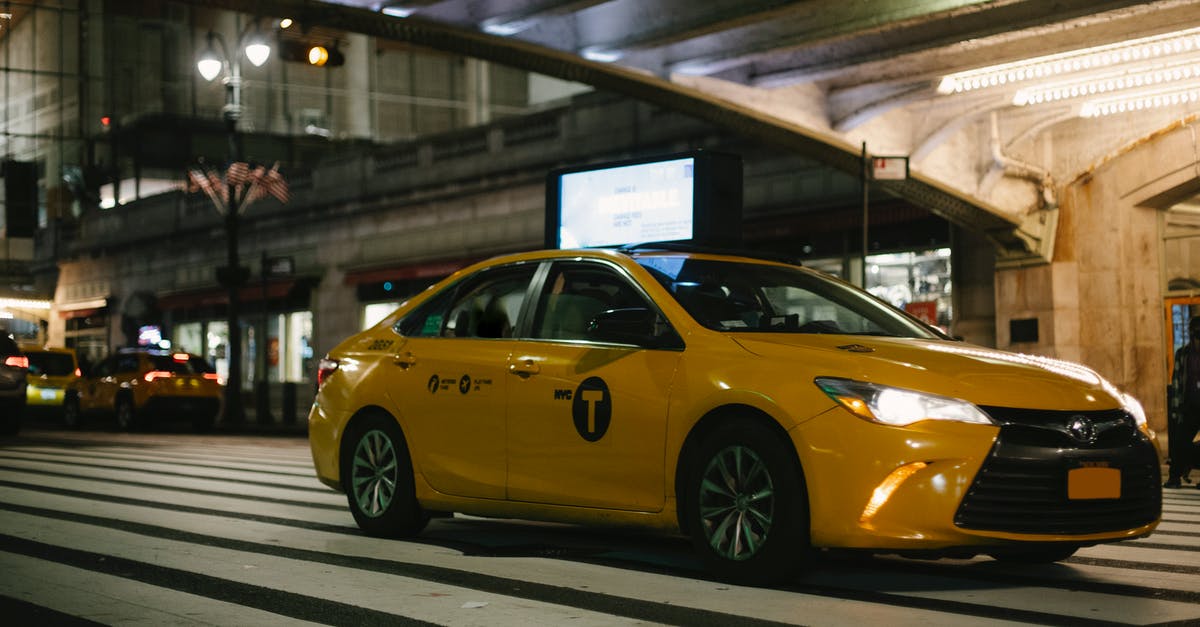 Driving in U.S. (Hawaii) with EU license written in Czech - Expensive yellow taxi car riding on New York City street under illuminated bridge at night