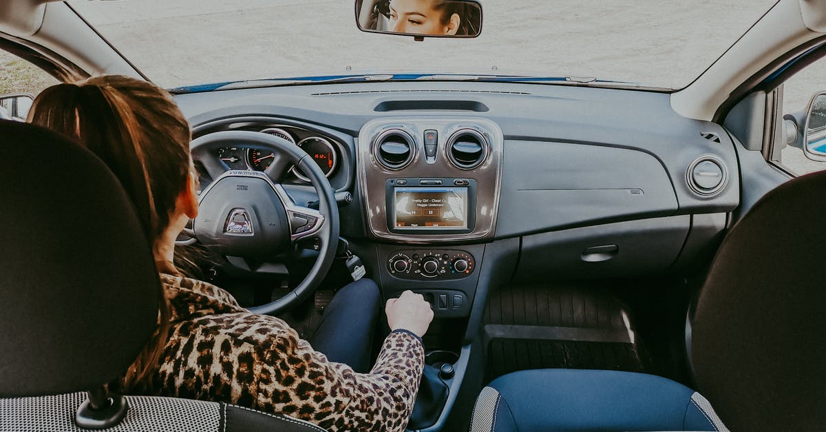 Driving non-GB registered car inside Low Emission Zone - Back view of modern woman in stylish fur coat driving car confidently looking away