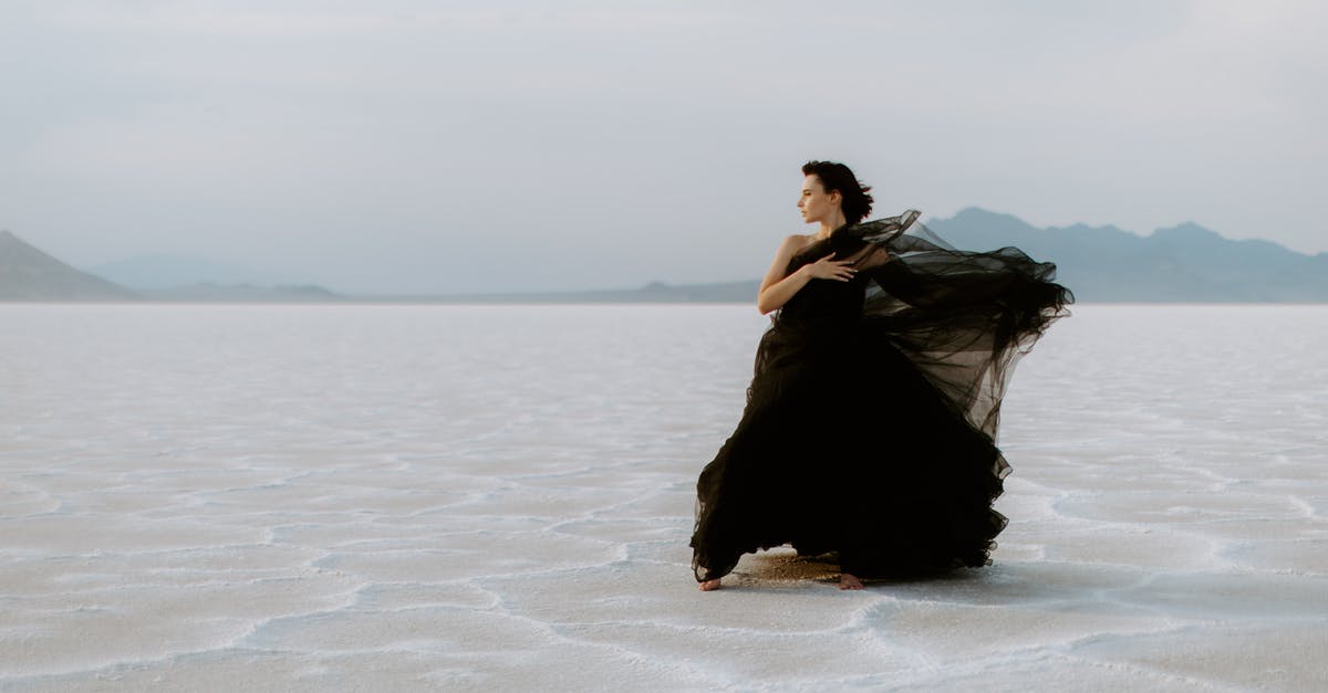 Driving On Utah Salt Flats - A Woman in Black Gown Standing on the Bonneville salt Flats