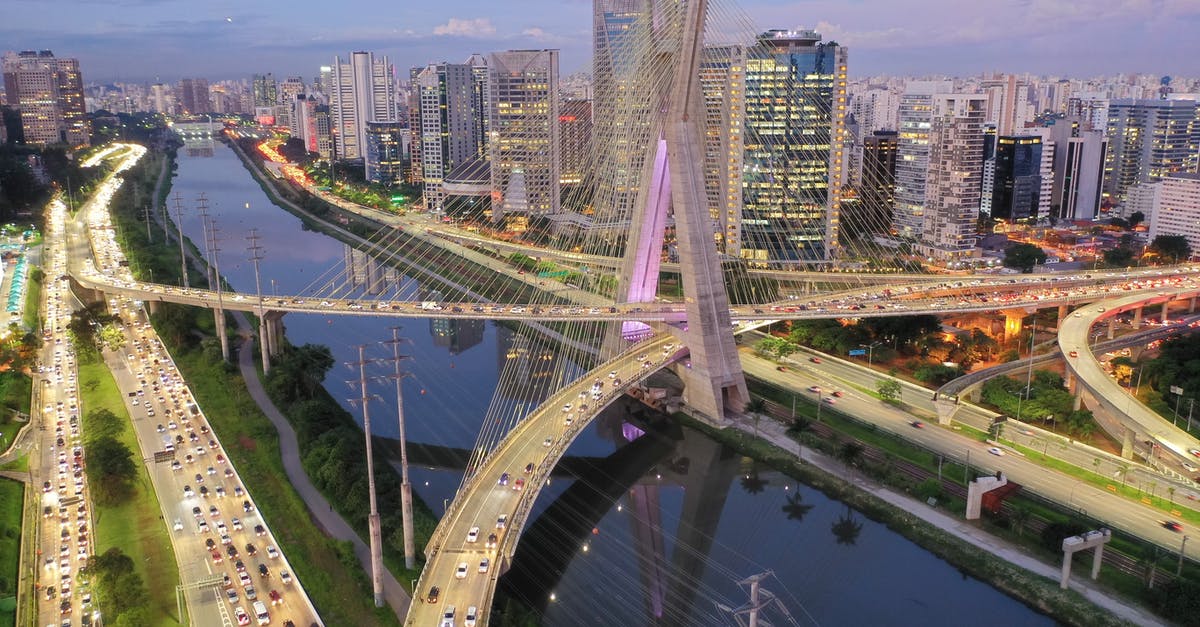 Dual Argentinian and US citizenship traveling to Brazil - From above of modern bridge crossing river with modern skyscrapers and green trees against cloudy and blue sky