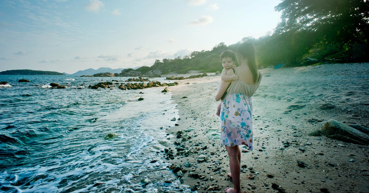 Dual Citizen Lebanese - Russian Travelling to Thailand - Woman Carrying Baby Beside the Seashore