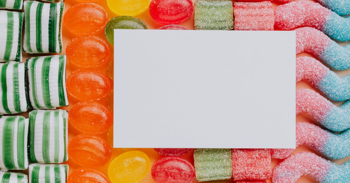 Dual citizenship different information [closed] - Top view closeup of blank paper card placed on multicolored various shapes yummy candies in light confectionery