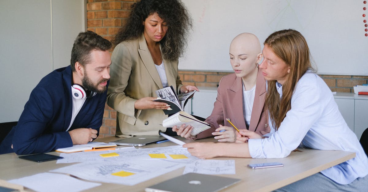 Dual citizenship different information [closed] - Group of multiracial businesspeople speaking and sharing data about project and analyzing reports in notebooks at table in office