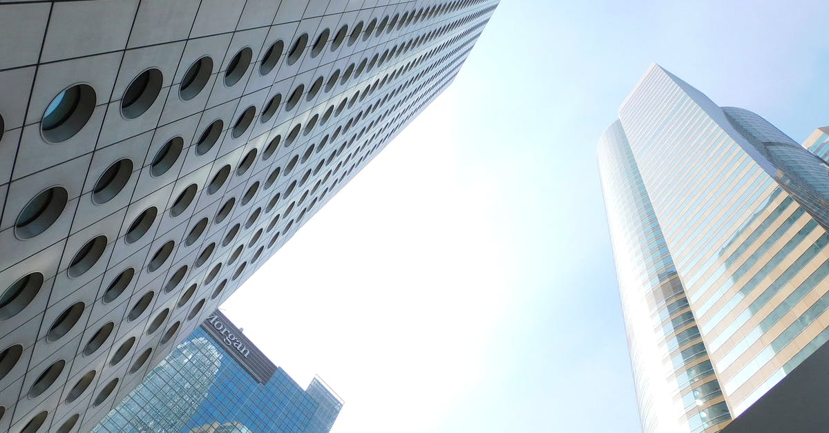 Duty free liquor from Hong Kong to China - From below of tall tower with round windows located in Hong Kong city near various skyscrapers with glass mirrored facades against cloudless blue sky