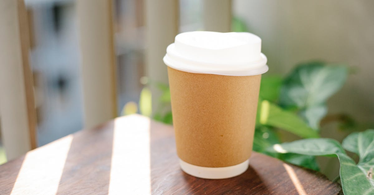 Early breakfast in London - Paper cup of coffee to go placed on table in cafeteria in sunny morning