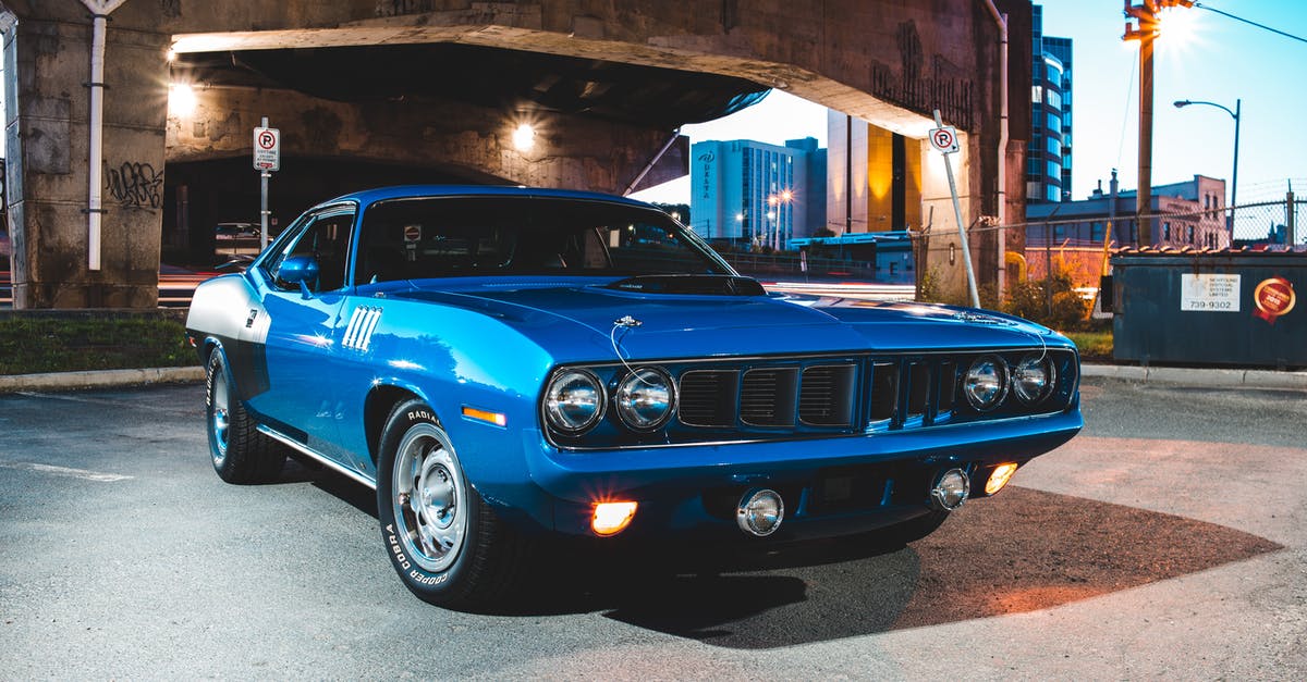 Early morning car rental at Belfast Ferry Port? - Blue retro automobile with round shiny headlights sparkling in lights of morning illumination