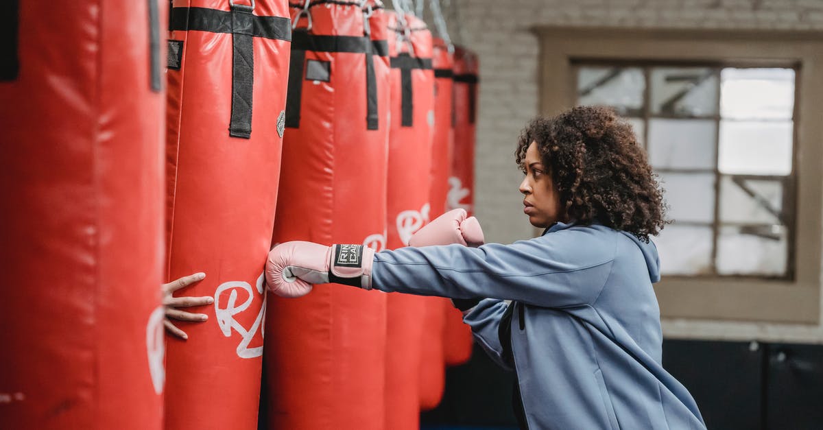 EasyJet underseat bag size - Focused black woman hitting punching bag held by trainer