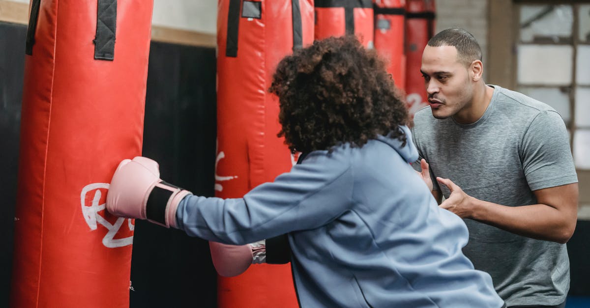 EasyJet underseat bag size - Ethnic male trainer cheering black woman hitting punching bag