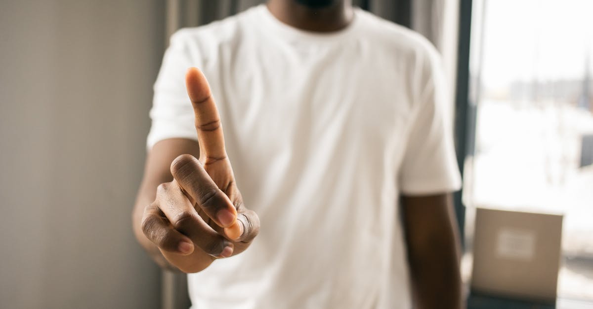 easyJet won't refund because it says 'no-show' but they denied boarding - Crop anonymous African American male in white t shirt showing stop gesture with index finger pointing up in light room on blurred background