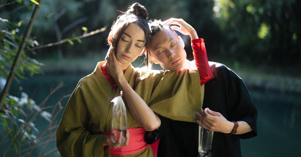 Eating fish eye in Japan - Man And Woman With Eyes Closed Holding Plastics With Fish