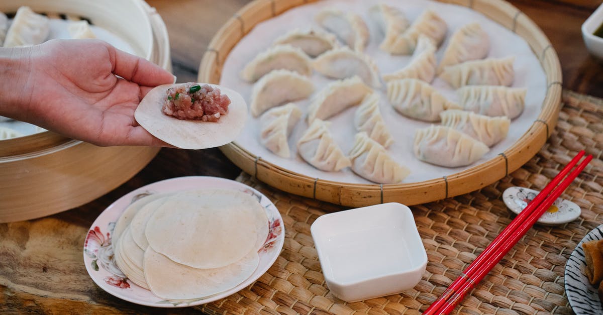 Eating pasta with raw minced meat in Italy - From above of crop anonymous female demonstrating dough circle with minced meat filling above table with dumplings at home