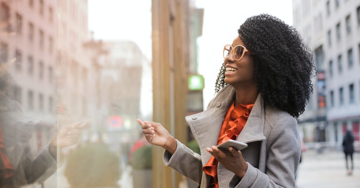 eBoarding passes of all family members on a single smartphone? - Happy black woman laughing on street