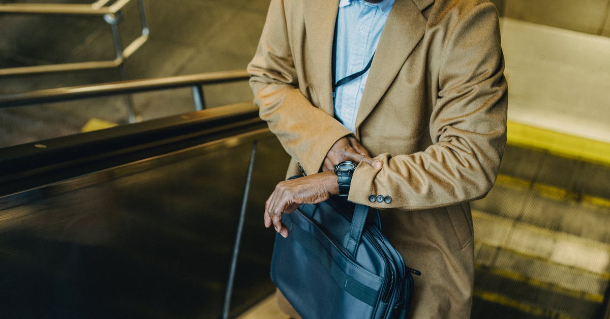 EC261 compensation for a delay between 3 and 4 hours - From above crop punctual African American businessman riding escalator and checking time on wristwatch while leaving metro station