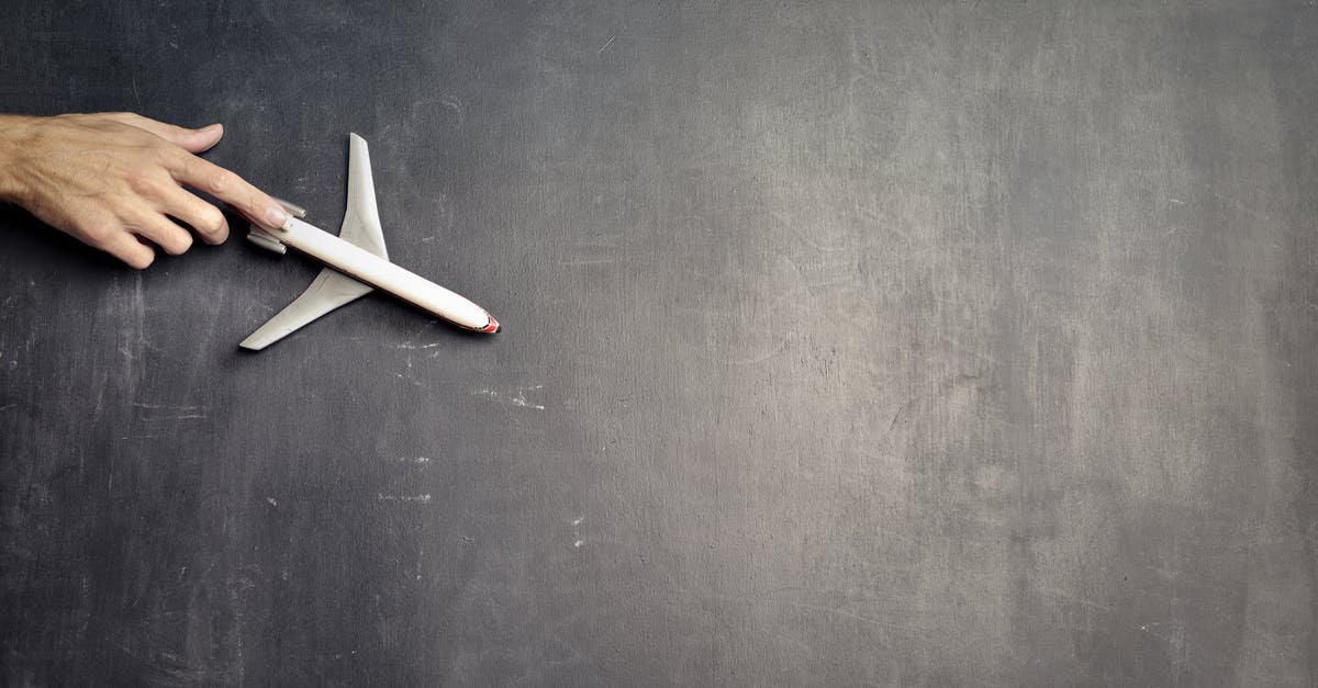 EC261 compensation when passenger resigned from delayed flight - Top view of crop anonymous person driving toy airplane on empty blackboard while representing journey concept