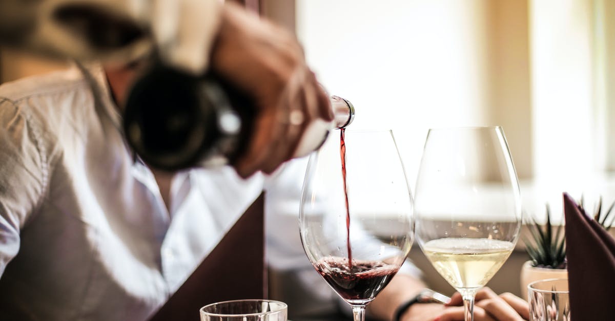 Economy ticket, but enjoy first-class service? - Crop man pouring red wine in glass in restaurant